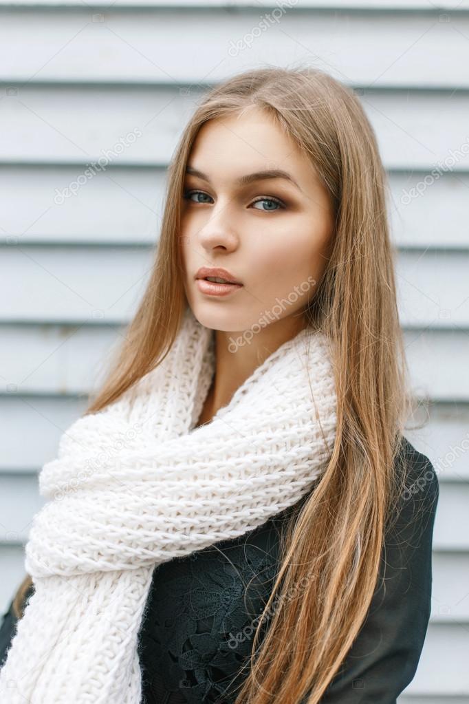Young pretty girl with a white knitted scarf in autumn day