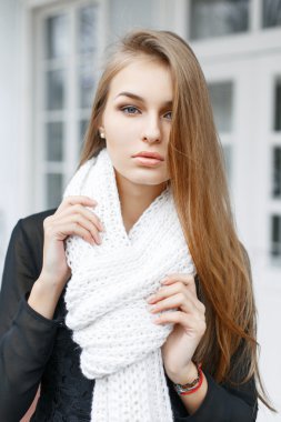 Young lovely woman with a white knitted scarf on the background of of vintage windows