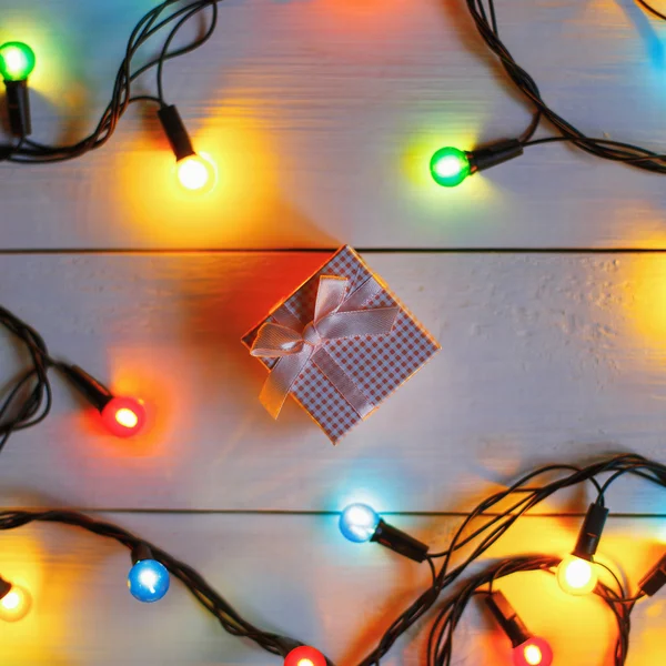 Gift in a box with a ribbon on the table near the lights — Stock Photo, Image