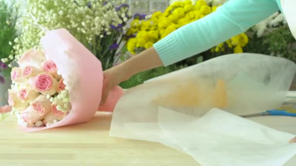 Negozio di fiori, organizzare bouquet, mano del fiorista avvolgendo carta bianca avvolgente intorno rosa bouquet rosa — Video Stock