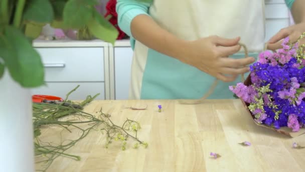 Flower shop, florist arranging statices bouquet, tying ribbons to make a bow — Stock Video