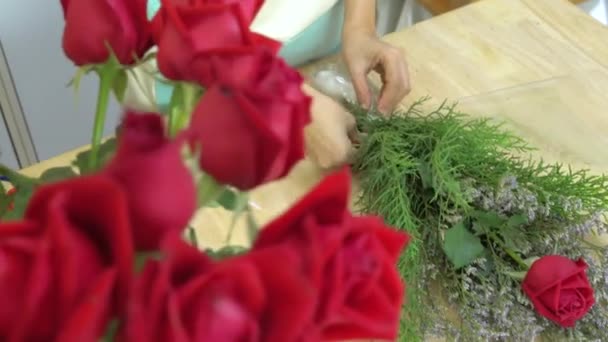 Ανθοπωλείο, ανθοπωλείο τακτοποιώντας ανθοδέσμη λουλουδιών, τακτοποίηση σελοφάν και φρέσκο τριαντάφυλλο μπουκέτο — Αρχείο Βίντεο