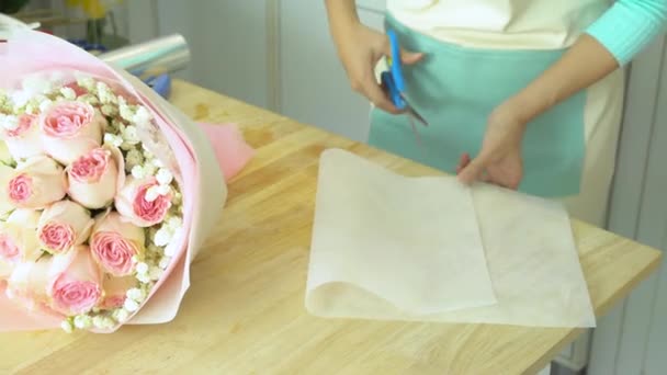 Loja de flores, arranjando buquê, mão de corte florista e papel de embrulho branco em torno do buquê rosa rosa — Vídeo de Stock