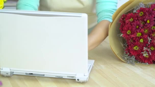 Flor loja, florista digitando no notebook, tomando a ordem e tocando mums buquê vermelho — Vídeo de Stock