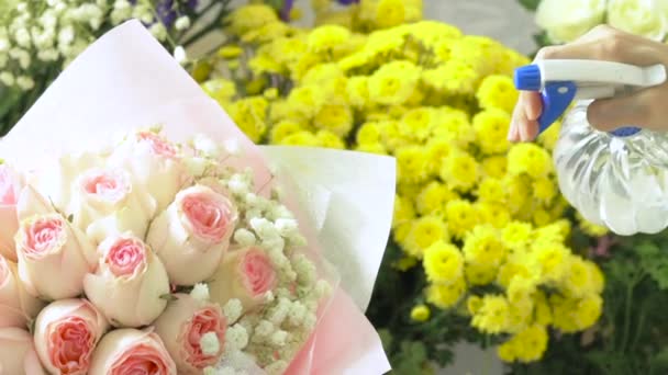 Vari fiori, rosa rosa bouquet, mano di fiorista spruzzare acqua dalla bottiglia spray su bouquet — Video Stock