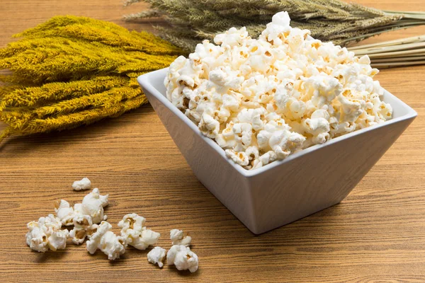 Popcorn v misce čtvercového tvaru s plodinou, žito vedle — Stock fotografie