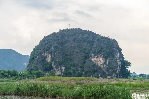 A steep small mountain in the middle of green field — Stock Photo, Image