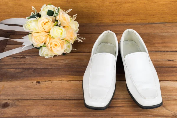 Wedding bouquet with groom's shoes on wood background — Stock Photo, Image