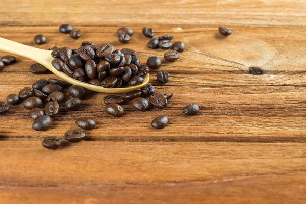 Coffee bean on wooden spoon, wooden table background — Stock Photo, Image