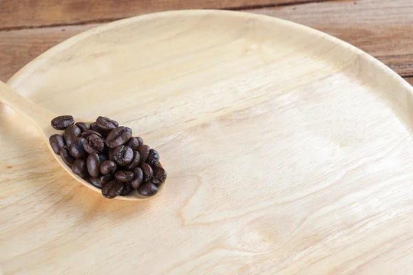 Coffee bean on wooden spoon, dish, table background — Stock Photo, Image