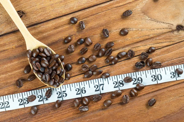 나무로 되는 숟가락, 나무 배경에 테이프 측정에 커피 콩 — 스톡 사진