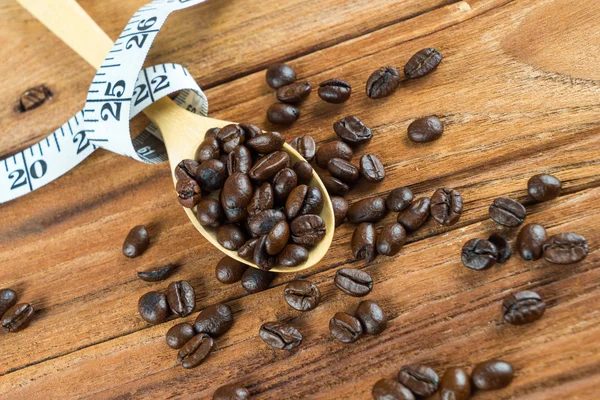 Kaffeebohne auf Holzlöffel, Maßband auf Holzgrund — Stockfoto