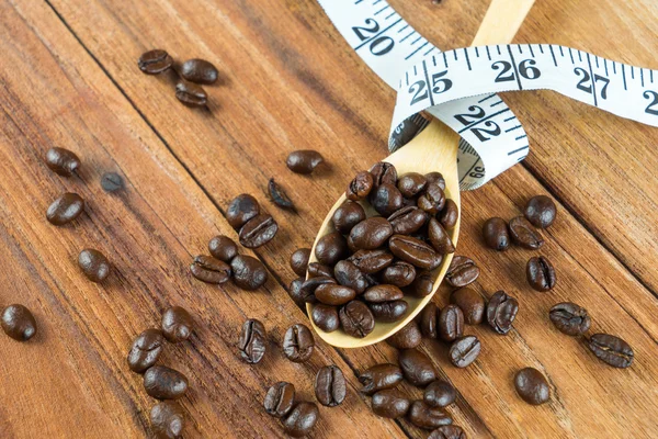 Kaffeebohne auf Holzlöffel, Maßband auf Holzgrund — Stockfoto