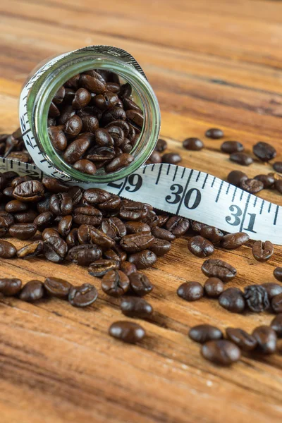 Kaffeebohne in Glasflasche mit Maßband auf hölzernem Hintergrund — Stockfoto