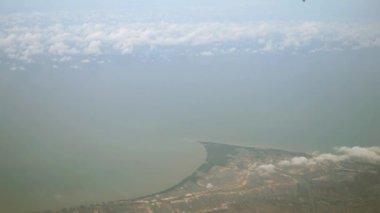 Yukarıdan, bulutların üstünden, aşağıdaki kırsal ve sahil manzarasını görüntüleyin