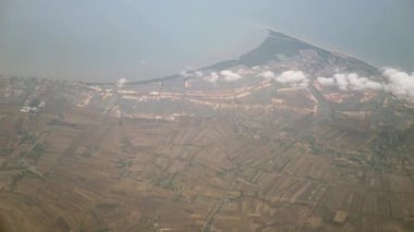 Yukarıdan, bulutların üstünden, aşağıdaki kırsal ve sahil manzarasını görüntüleyin