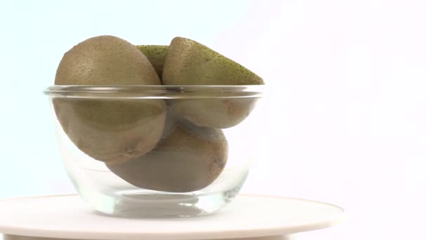 Lägga ner skål med färsk grön kiwi, skål roterande, långsam — Stockvideo