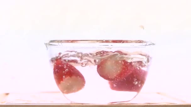 Fresh, red strawberries poured into splashed water in a bowl, slow — Stock Video
