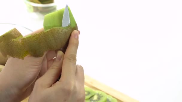 Een kiwi peeling met een mes — Stockvideo