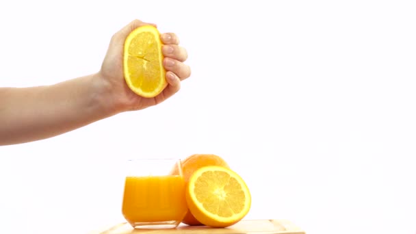 Χέρι στριμώχνονται φρέσκου λεμονιού σε ένα ποτήρι χυμό πορτοκάλι — Αρχείο Βίντεο
