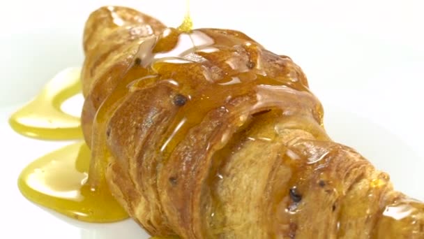 Honig auf Croissant gießen, Croissant mit Honig, rotierend, langsam — Stockvideo