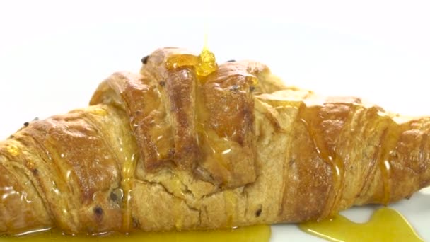 Pouring honey on croissant, rotating, close-up, slow — Stock Video