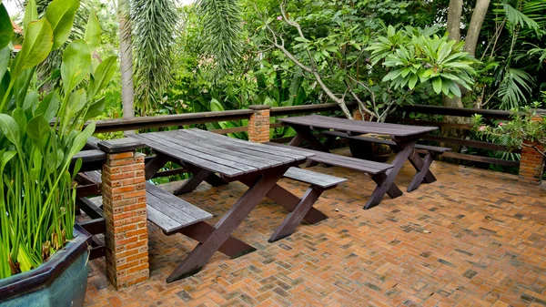 Cadeiras de madeira e mesa na varanda em um jardim planta verde . — Fotografia de Stock