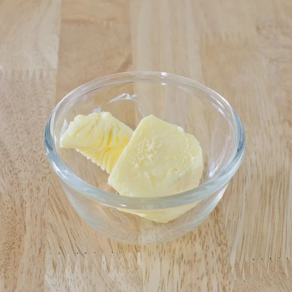 Bastone di burro, tagliato, in ciotola di vetro sul tavolo di legno . — Foto Stock