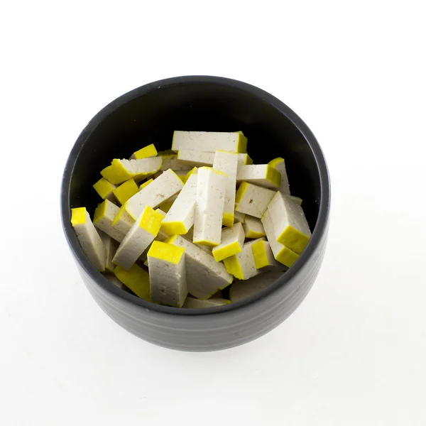 Świeże żółte tofu w czarnej misce izolować białe tło — Zdjęcie stockowe
