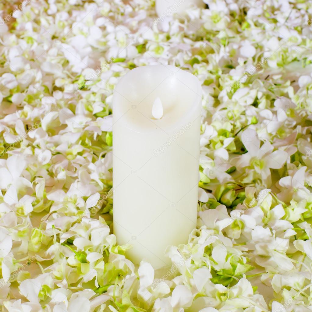 The big white candle in a wreath from artificial flowers. A wedd