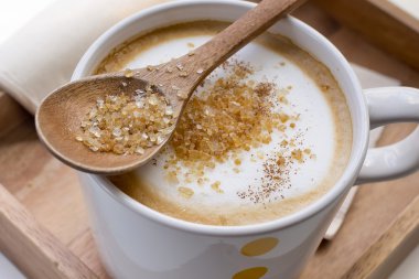 Kahverengi şeker bir kaşık ve bir fincan kahve Cappuccino