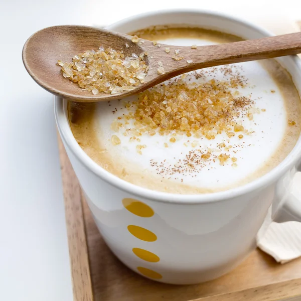 Brown sugar on a spoon and a cup of coffee Cappuccino — Stock Photo, Image