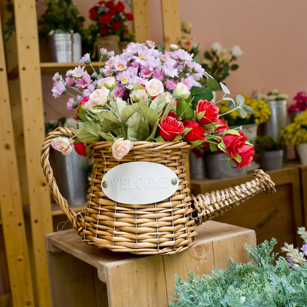 Fleurs colorées en rotin arrosoir sur table en bois — Photo