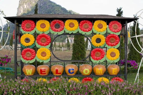 Willkommensschild im Garten mit bunten Blumen im Hintergrund — Stockfoto