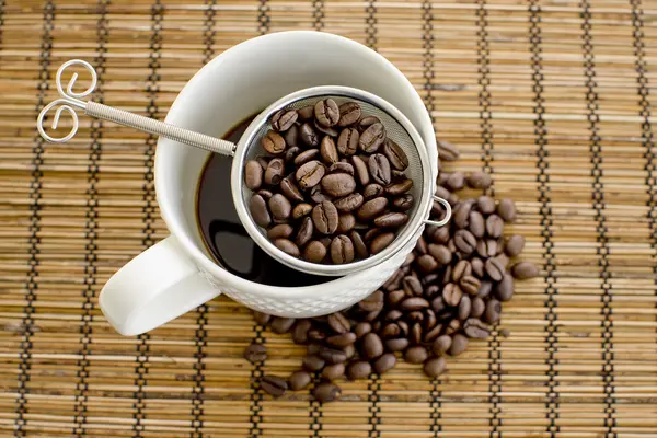 Xícara de café e café em uma mesa de madeira — Fotografia de Stock