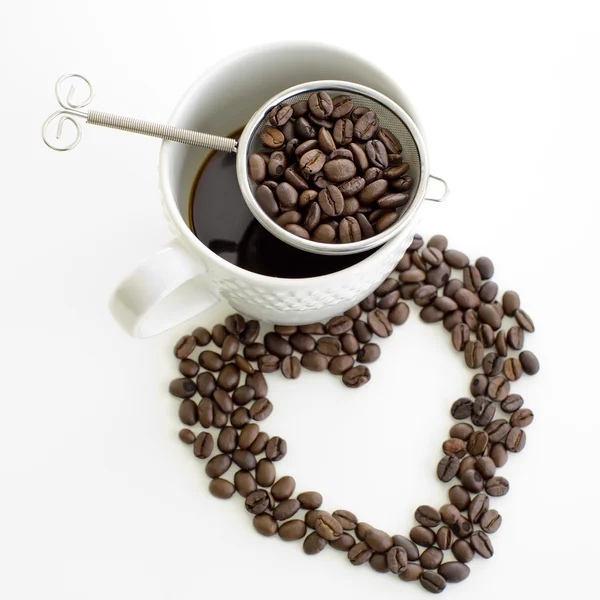Xícara de café e café feijão linha forma do coração no fundo branco — Fotografia de Stock