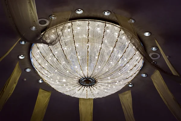 Shining chandelier hanging on a ceiling in hotel — Stock Photo, Image