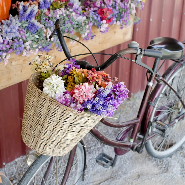 Bruin vintage fiets met bloemen op thered muur. — Stockfoto