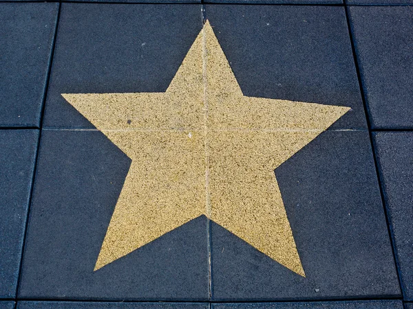 Dark blue brick floor with a painting of a big gold star. — Stock Photo, Image