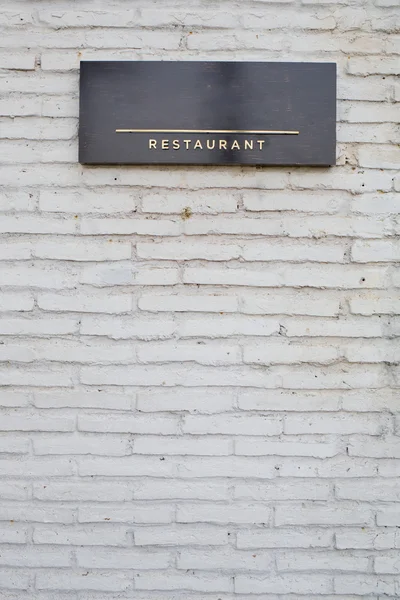 Sinal de restaurante na placa de mármore preto na parede de tijolo branco — Fotografia de Stock