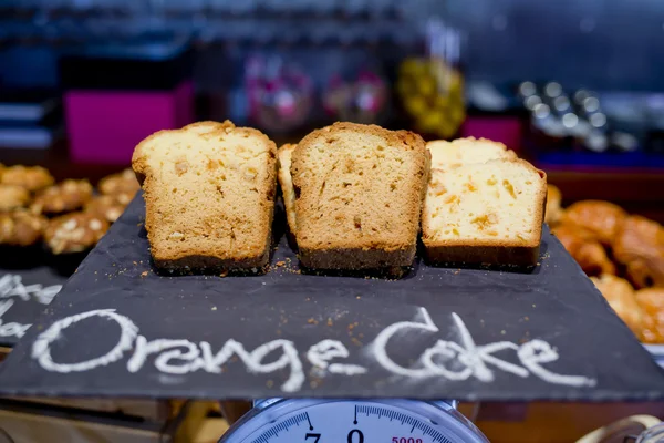 Pães de laranja fatiados na placa preta e esquete de mão de bolo de laranja — Fotografia de Stock