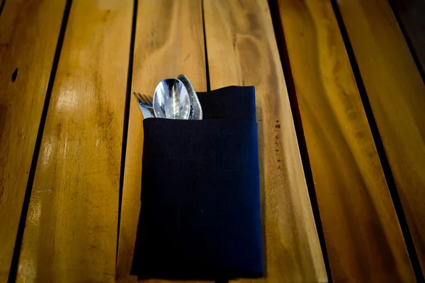 포크와 숟가락 어두운 파란색 천으로, 나무 테이블 배경에서 — 스톡 사진