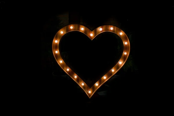 Signo del corazón con bombilla aislada sobre fondo negro —  Fotos de Stock