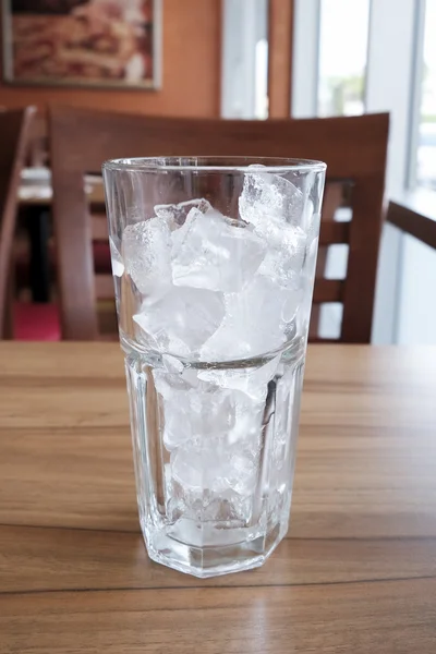 Vetro vuoto con cubetti di ghiaccio sul tavolo di legno — Foto Stock