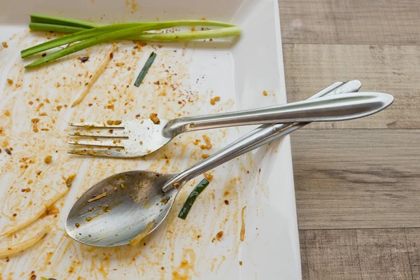 Piatto vuoto ma ha ancora cipollotti dopo il cibo sul tavolo — Foto Stock