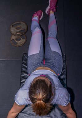 Spor salonunda çeşitli egzersizler yapan genç bir kadın.