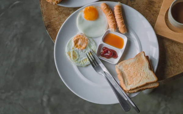 Kızarmış Yumurtalı Kahvaltı Sosis Beyaz Tabakta Ekmek Ahşap Bir Masaya — Stok fotoğraf