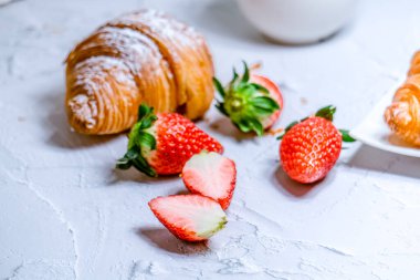 Kremalı şeker ve taze çilek serpiştirilmiş kruvasanlardan oluşan kıtasal bir kahvaltı..