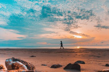 Denizin arka planında yürüyen insanların gölgeleriyle eski ahşap bir masa.