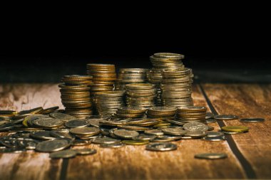 Bozuk paralar, yüksek ve düşük eğimli ve bozuk paralar halinde eski ahşap bir masa üstüne ve siyah bir arkaplan üzerine istiflenmiş bir şablon halinde yere saçılmıştır..